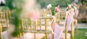 rows of chairs with pink floral and ribbon decor on the aisle chairs